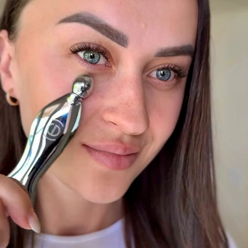 Person using a Gua Sha tool near their eye with a neutral background