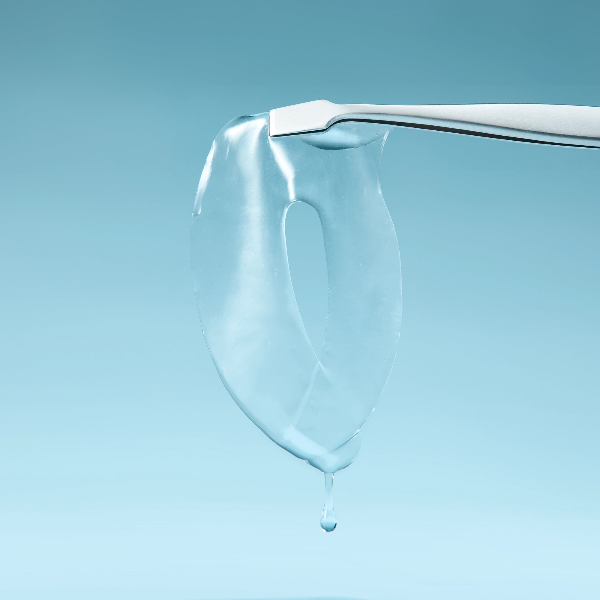 Tweezers hold In My Eyes eye patch (eye mask) with dripping essence, for sensitive dry eyes, on blue.